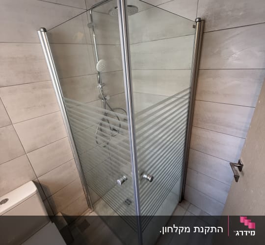 מקלחון זכוכית עם דלתות מתכת בחדר אמבטיה